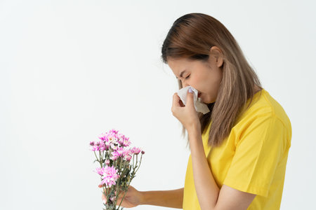 Pollen Allergies, asian young woman sneezing in a handkerchief or blowing in a wipe, allergic to wild spring flowers or blossoms during spring. allergic reaction, respiratory system problemsの写真素材