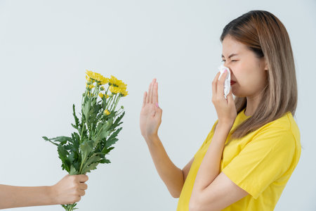Pollen Allergies, asian young woman sneezing in a handkerchief or blowing in a wipe, allergic to wild spring flowers or blossoms during spring. allergic reaction, respiratory system problemsの写真素材