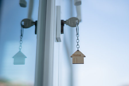Landlord key for unlocking house is plugged into the door. Second hand house for rent and sale. keychain is blowing in the wind. mortgage for new home, buy, sell, renovate, investment, owner, estateの写真素材