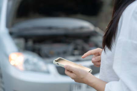 breakdown, broken car, repair. Woman uses mobile phone check insurance premiums through application...