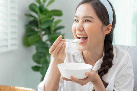 healthy food. Beautiful female girl enjoy eat yogurt, granola, fresh fruits on breakfast health in house. Happy young woman smile on morning good emotion. dieting, detox, diet, clean eat, vegetarianの写真素材