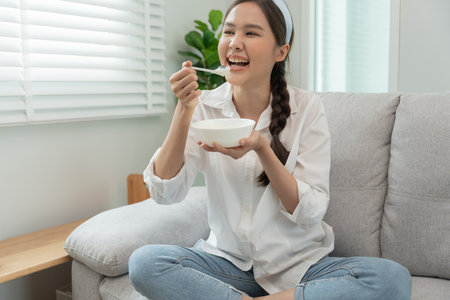 healthy food. Beautiful female girl enjoy eat yogurt, granola, fresh fruits on breakfast health in house. Happy young woman smile on morning good emotion. dieting, detox, diet, clean eat, vegetarianの写真素材