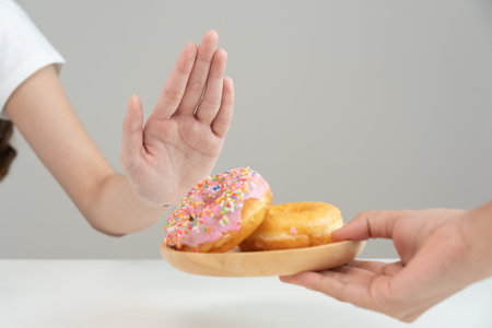 Diet and dieting. Beauty slim female body confuse donut. Woman in exercise clothes achieves weight loss goal for healthy life, crazy about thinness, thin waist, nutritionist.の写真素材