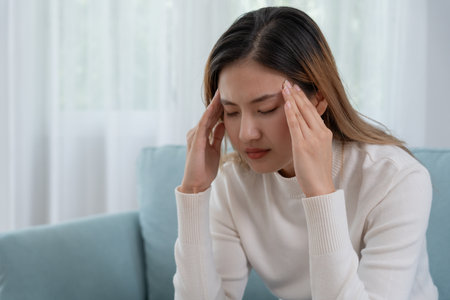Headache, female having migraine pain, bad health, Asian woman feeling stress and headache, Office syndrome, sad tired touching forehead having migraine or depression, irritated girl, sadness griefの写真素材