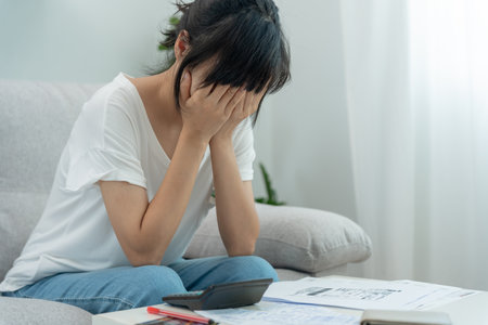 Stressed and headache asian woman with large bills or invoices no money to pay to expenses and credit card debt. shortage, Financial problems, mortgage, loan, bankruptcy, bankrupt, poor, empty walletの写真素材