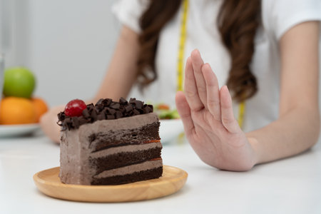 Beauty slim female body confuse chocolate cake. Woman in restaurant achieves weight loss goal for healthy life, crazy about thinness, thin waist, nutritionist. Diet, body shape.の写真素材
