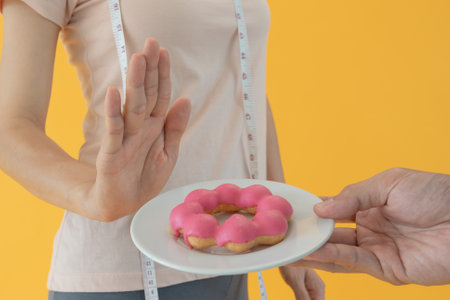 Diet and dieting. Beauty slim female body confuse donut. Woman in exercise clothes achieves weight loss goal for healthy life, crazy about thinness, thin waist, nutritionist.の写真素材