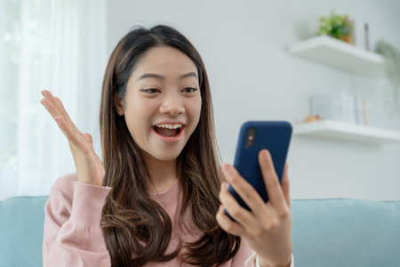 Asian beautiful woman exited surprise face expression . female feels shocked with the phone. exciting smile and happy adorable rejoices. Very enjoy and fun relax time. wow, girl holding smartphone.の写真素材