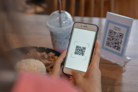 Woman use smartphone to scan QR code to pay in cafe restaurant with a digital payment without cash. Choose menu and order accumulate discount. E wallet, technology, pay online, credit card, bank app.の写真素材