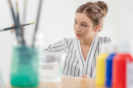 Professional female artist girl use paintbrush in abstract art for create masterpiece. painter paint with watercolors or oil in studio house. beautiful woman enjoy painting as hobby. work recreationの写真素材