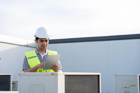 Asian maintenance engineer works on the roof of factory. contractor inspect compressor system and...
