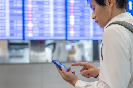 Business man using mobile phone to book plane ticket through online application, sitting on travel checking travel time on board at airport, travel, payment, due, booking, online, check inの写真素材