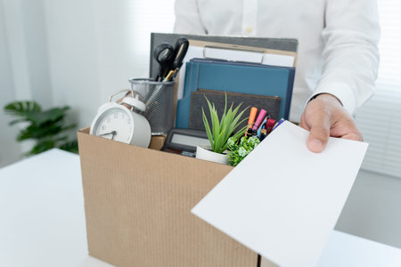 Stressful businessmen will resign from the company. He is lifting a brown paper box that holds...