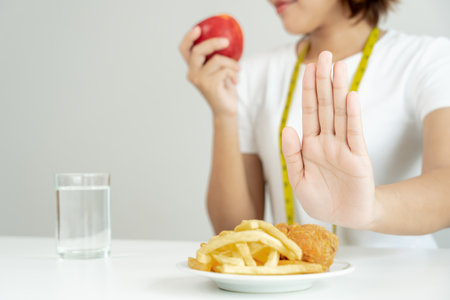slim female body confuse French fries and fried chicken. Woman in restaurant achieves weight loss goal for healthy life, crazy about thinness, thin waist, nutritionist. Diet, body shape.の写真素材
