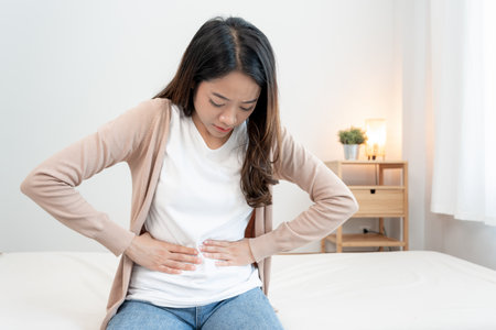 stomach ache. Asian women have abdominal pain, indigestion, gastritis, menstrual cramps, flatulence, diarrhea, distention, colon cancer, belly inflammation problem, suffer food poisoning, abdomenの写真素材