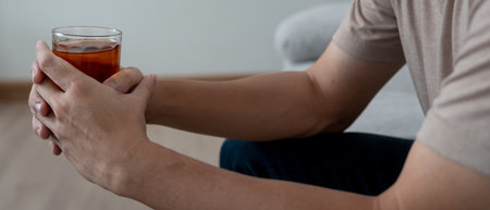 Depressed young Asian man addicted feeling bad drinking whiskey alone at home, stressed frustrated lonely drinking alcohol suffers from problematic liquor, alcoholism, life and family problemsの写真素材