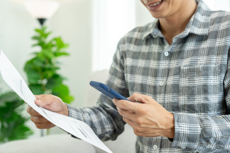 business man use phone to scan barcode or QR codes to pay credit card bill after receiving document invoice online. payment, receive, paying electricity, digital payments without money, technologyの写真素材