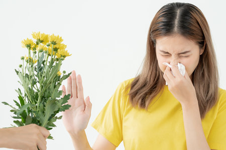 Pollen Allergies, asian young woman sneezing in a handkerchief or blowing in a wipe, allergic to wild spring flowers or blossoms during spring. allergic reaction, respiratory system problemsの写真素材