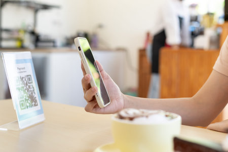 Woman use smartphone to scan QR code to pay in cafe restaurant with a digital payment without cash....
