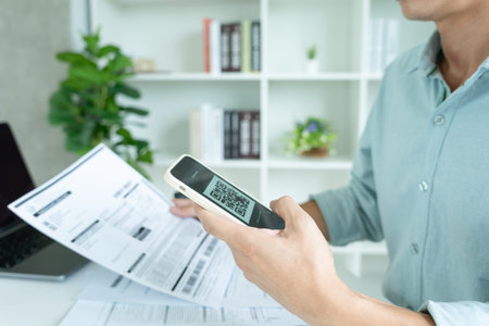 business man use phone to scan barcode or QR codes to pay credit card bill after receiving document...