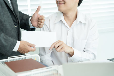 Businessmen receive salary or bonuses from management or Boss. Company give rewards to encourage work. Smiling businessman enjoying a reward at the desk in the office.の写真素材