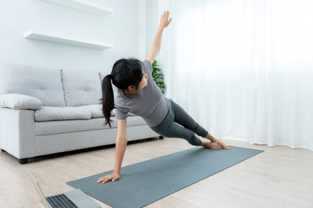 Slim woman practicing yoga on room of her condo or home. Asian woman doing exercises in morning. balance, meditation, relaxation, calm, good health, happy, relax, healthy lifestyle, diet, slimの写真素材