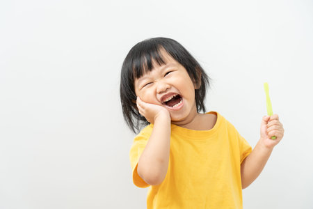 little asian girl presses hand to cheek, suffers from pain in tooth. Teeth decay, dental problems,...