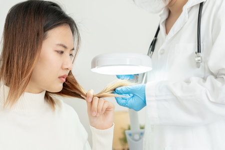 Specialist of hair recheck hair of Asian woman, damaged hair, hair loss, thinning problem, vitamin deficiency, baldness, postpartum, biotin, zinc, menstrual or endocrine disorders, hormonal imbalanceの写真素材