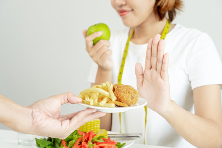 Beauty slim female body confuse French fries and fried chicken. Woman in restaurant achieves weight loss goal for healthy life, crazy about thinness, thin waist, nutritionist. Diet, body shape.の写真素材