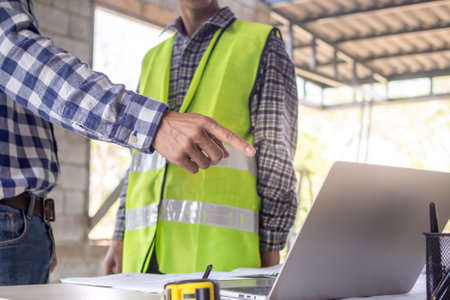 Engineers team use laptop and check the blueprint on site. Contractor and inspector inspection construction during project.civil Forman check quality assurance. Audit, inspect, quality control.の写真素材