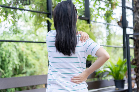 woman holding her lower back while and suffer from unbearable pain health and problems, chronic back pain, backache in office syndrome, scoliosis, herniated disc, muscle inflammationの写真素材
