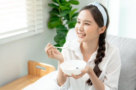 healthy food. Beautiful female girl enjoy eat yogurt, granola, fresh fruits on breakfast health in house. Happy young woman smile on morning good emotion. dieting, detox, diet, clean eat, vegetarの写真素材