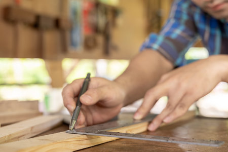 man owner a small furniture business is preparing equipment for work. carpenter male is adjust wood to the desired size. architect, designer, Built-in, professional wood, craftsman, workshopの写真素材