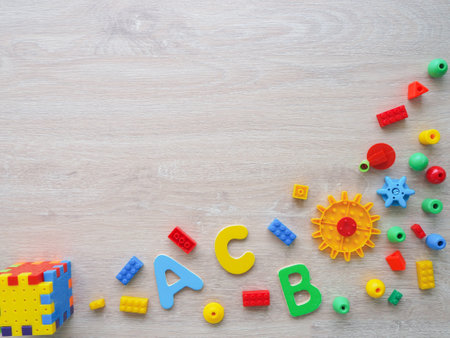 A colorful assortment of building blocks and letters, including are scattered across a wooden surfaceの写真素材