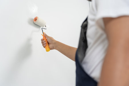 painter man, brush in hand for products to restore and paint the wall, indoor the building site of a house, wall during painting, renovation, painting, contractor, Architect, construction workerの写真素材