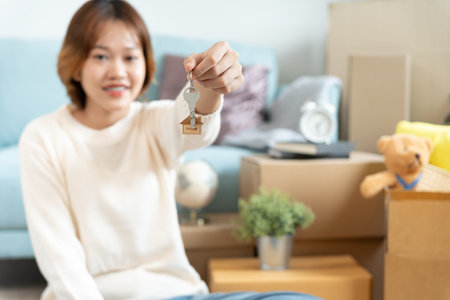 Moving house, relocation. Woman hold key house keychain in new apartment. move in new home. Buy or...