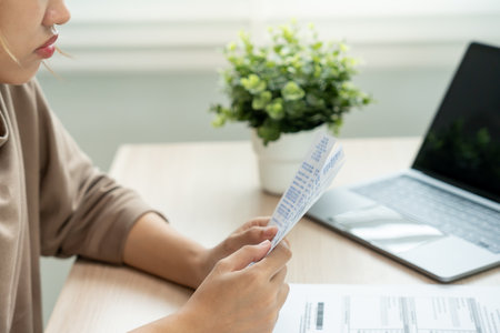 Stressed and headache asian woman with large bills or invoices no money to pay to expenses and credit card debt. shortage, Financial problems, mortgage, loan, bankruptcy, bankrupt, poor, empty walletの写真素材