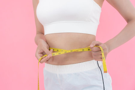 Diet and dieting. Beauty slim female body use tape measure. Woman in exercise clothes achieves...