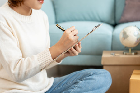 Move house, relocation. Woman using household checklist for new apartment Inside the room are...
