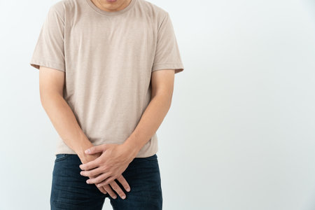 Man hold hand in front of private parts feeling discomfort from disease and inflammation. Venereal, testicular cancer. bladder problems, erectile dysfunction, premature ejaculation, prostate cancerの写真素材