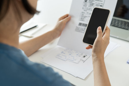 woman use phone scan barcode or QR codes to pay credit card bill after receiving document invoice. payment, receive, paying electricity, digital payments, technology, scanning, financial transactionsの写真素材