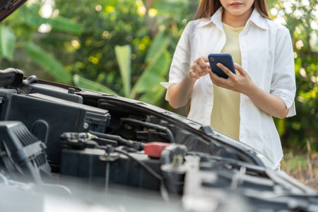 breakdown, broken car, repair. Woman uses mobile phone check insurance premiums through application...