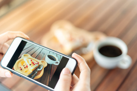 restaurant owner takes a picture of the food on the table with a smartphone to post on a website. Online food delivery, ordering service, influencer, review, social media, share, marketing, interest.の写真素材