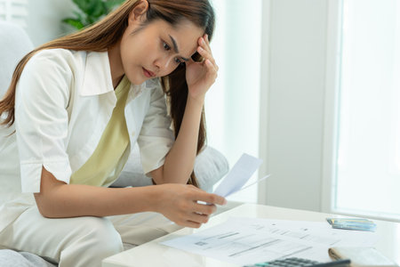 Stressed and headache asian woman with large bills or invoices no money to pay to expenses and credit card debt. shortage, Financial problems, mortgage, loan, bankruptcy, bankrupt, poor, empty walletの写真素材