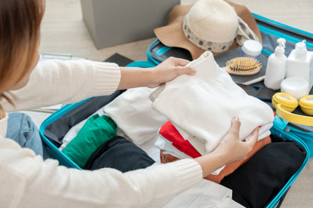Travel bag. female are checking the detail and quantity of items used during the trip. Young women are prepare clothes and personal belongings. Pack your luggage before travel.の写真素材