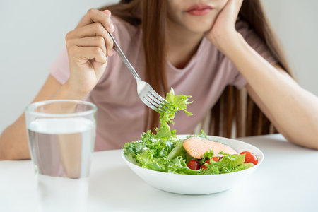 slim body asian women very bored diet food, dieting female choose low calories food for diet. Good healthy food. weight lose, balance, control, reduce fat, routines, exercise, body shapeの写真素材