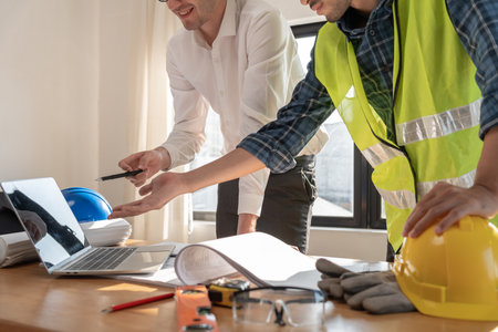 Engineers use laptops and check the blueprint. Contractor review drawing before start project civil. Prepare construction project planning concept.の写真素材