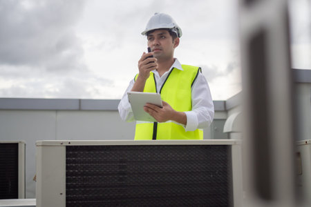 Asian maintenance engineer works on the roof of factory. contractor inspect compressor system and plans installation of air condition systems in construction. technology, onlineの写真素材