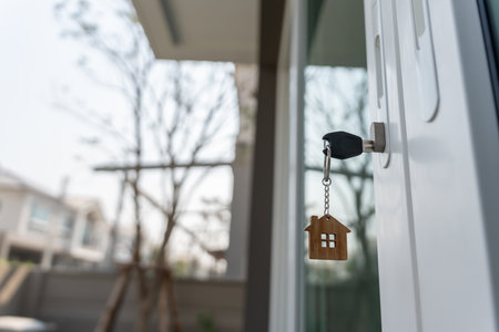 Landlord key for unlocking house is plugged into the door. Second hand house for rent and sale. keychain is blowing in the wind. mortgage for new home, buy, sell, renovateの写真素材