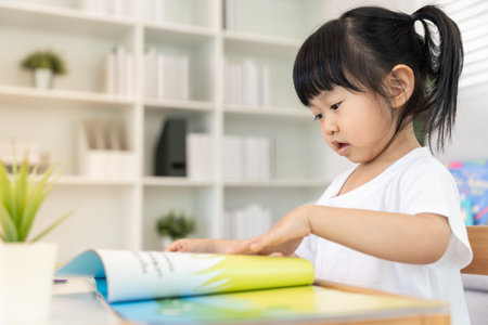 Happy Asian children relax read book at home. daughter and reading a story. learn development, childcare, laughing, education, storytelling, practice, imagineの写真素材